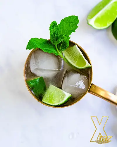 a cocktail of vodka named moscow mule with limes and ice in a yellowish glass