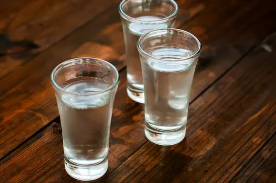 3 glasses with vodka on wooden table