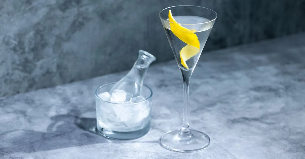 Glass of extra dry martini and ice cubes in another glass.